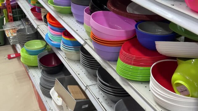 Colorful plastic and ceramic kitchenware array on retail store shelves, showcasing diverse dining