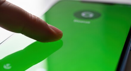 Finger engaging touchscreen interface of cellular device displays vivid green screen