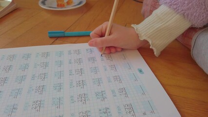 A focused young student diligently solves complex math in a notebook. This high-quality footage captures academic excellence, disciplined study habits, and the essence of early childhood education.