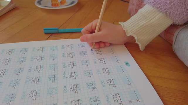 A focused young student diligently solves complex math in a notebook. This high-quality footage captures academic excellence, disciplined study habits, and the essence of early childhood education.