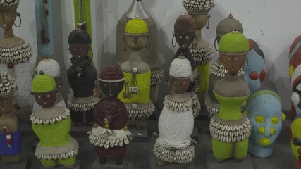 Close-up shot of artistic handmade figurines representing Gnaoua musicians. The dolls feature traditional colorful attire and hats adorned with cowrie shells, displayed in a shop in Essaouira.