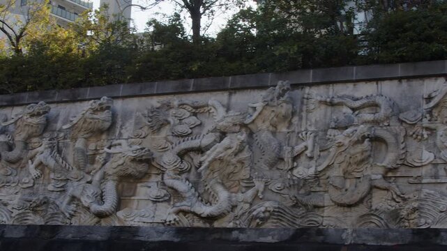 Pan across elaborate, ornate dragon relief in stone on wall in Japan