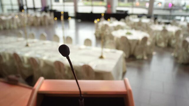 Making a big speech at a fancy wedding venue - microphone in front of set tables