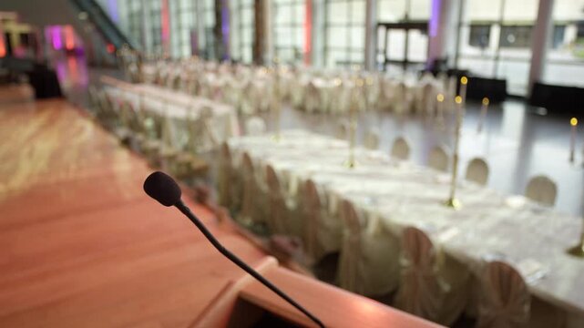 Making a big speech at a fancy wedding venue - microphone in front of set tables