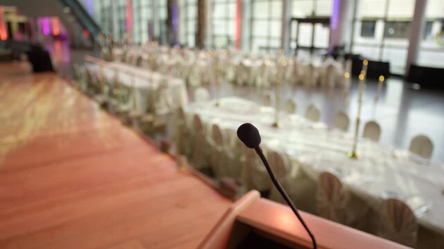 Making a big speech at a fancy wedding venue - microphone in front of set tables