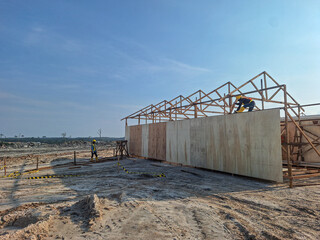 A large wooden structure under construction, surrounded by building materials and rocks. Selective focus.
