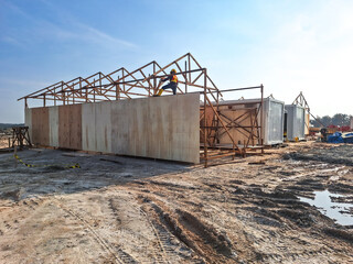 A large wooden structure under construction, surrounded by building materials and rocks. Selective focus.