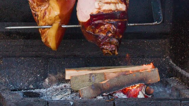 Traditional Pork Knuckle Rotating on Spit Over Open Wood Fire