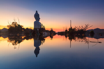 Serene Buddha Statue Reflection at Sunset in water (Phra Chom Nam) in Khao Rakham Reservoir at Trat Province of Thailand