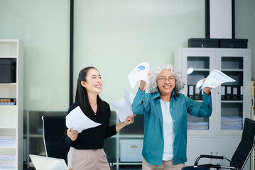 Naklejka premium Happy Asian businesswomen celebrating teamwork success in office. Corporate achievement, business victory, motivation
