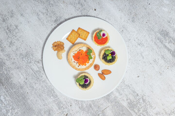 Elegant gourmet appetizer platter with caviar, crackers, and nuts on a textured background