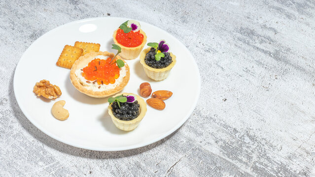 Assorted gourmet appetizers with caviar served on a plate with nuts and crackers