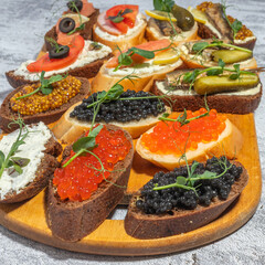 An assortment of gourmet open sandwiches with various toppings including caviar, vegetables, and herbs on a serving board.
