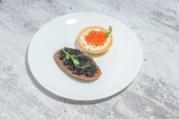 Elegant appetizer presentation with black and red caviar on a rustic plate, top view.