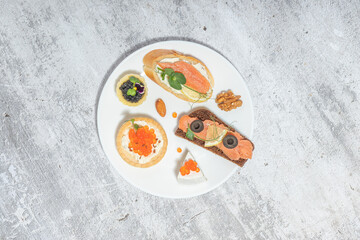 An elegant arrangement of gourmet appetizers on a white plate with a textured background.