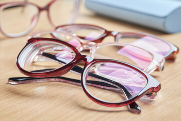 Multiple pairs of stylish red glasses for vision correction and eye care, with a blue case in the background.