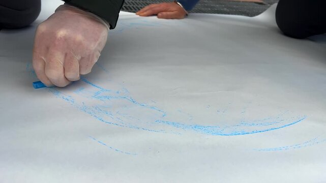 Street level view: Artists trace manhole cover on paper with charcoal