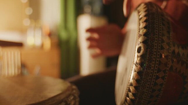 Static close-up of hands playing a traditional darbuka in cozy warm lighting.