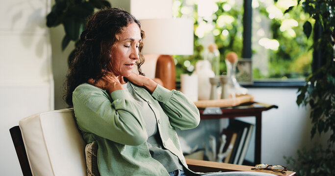 Neck pain, headache and stress with woman in living room of home for burnout, discomfort or fatigue. Brain fog, dizzy and muscle massage with mature person in apartment for recovery or symptom relief