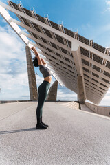 Sporty woman practicing yoga asana under modern solar panel installation, promoting renewable energy and healthy lifestyle
