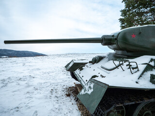 Close up of a World War II Soviet T-34 tank turret and gun in Death Valley near Kapišová, Slovakia. Preserved armored vehicle in snowy landscape showing heavy terrain and battlefield conditions.  © Marek