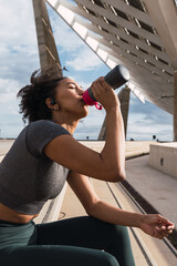 Young woman drinking water after training outdoors