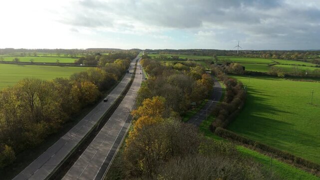 Aerial drone view of dual lane motorway highway with traffic and vehicles travelling, sunny day United Kingdom