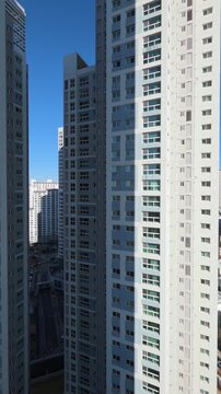 Vertical drone shot panning right to reveal dense cluster of towering modern residential skyscrapers and apartment complexes in downtown Daegu South Korea