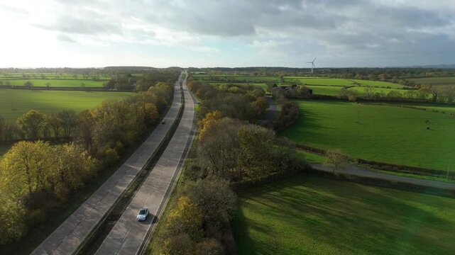 Cinematic aerial drone shot of busy dual lane highway with cars and trucks driving on a sunny day in United Kingdom transportation network