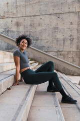 Young sportswoman resting on urban steps after exercising, enjoying a moment of peace