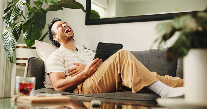 Man, tablet and laugh on sofa, relax and streaming service for funny movies in living room at home. Person, tech and happy with app, video and comedy film on web, couch or subscription at apartment