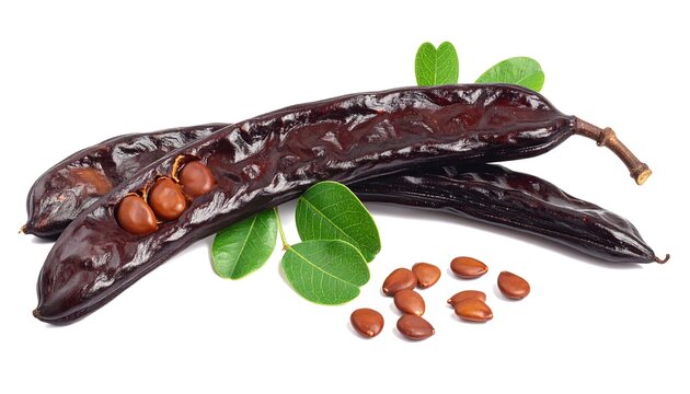 Carob Pods with Seeds and Green Leaves on White Background.
