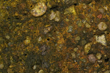 The wall's surface is covered in greenish-brown moss. The gravel mixture that makes it up can be seen scattered randomly.
