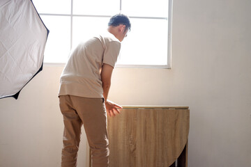 Man Setting up Wooden Table Near Window in Modern Room