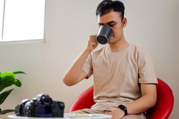 Young Man Enjoying Coffee while Sitting with Camera Nearby