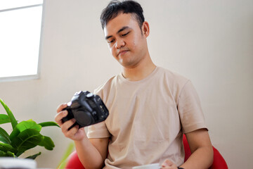 Young Man Reviewing Photos on Camera in Modern Workspace
