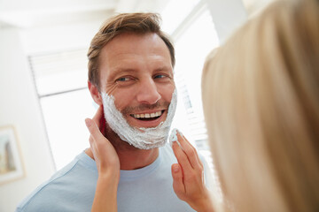 Happy, couple and man in bathroom with shaving cream for cleaning routine, grooming and hygiene in home. House, helping and person with woman for self care, hair removal and bonding in morning