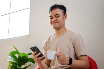 Relaxed Man Enjoying Coffee While Browsing on His Smartphone