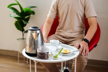 Man Enjoying Breakfast with Kettle and Coffee cup on Small Table