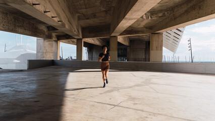 Sporty woman running in urban environment near the sea, enjoying her daily workout