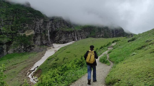 Exploring the scenic Neelkanth Base Camp trail: A solo hiker walking in the lush green mountains of Badrinath.