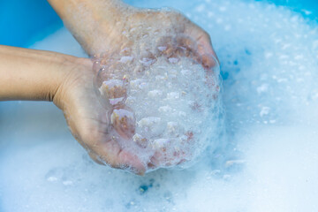 Fototapeta premium Hands Holding Soap Bubbles in Clean Water, Close-up, Wash hands hygiene, cleanliness, handwashing routine, and disease prevention through proper sanitation