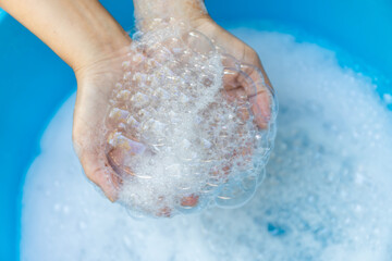 Fototapeta premium Hands Holding Soap Bubbles in Clean Water, Close-up, Wash hands hygiene, cleanliness, handwashing routine, and disease prevention through proper sanitation