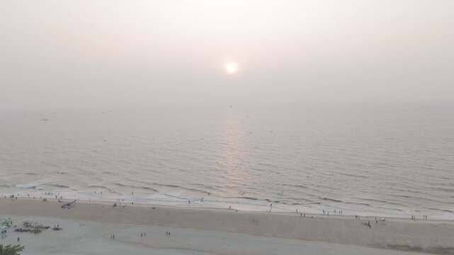 Sunset at Mobor Beach, South Goa in winter, showing white sand shoreline, calm Arabian Sea, setting sun, and lush coastal Goan vegetation with palm trees creating a serene tropical seascape.