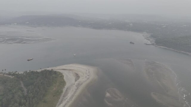 Aerial view of Morjim turtle nesting beach in Goa during winter, showing small fishing boats along the shoreline, gentle ocean waves, sandy coast, and the Chapora River visible in the background.