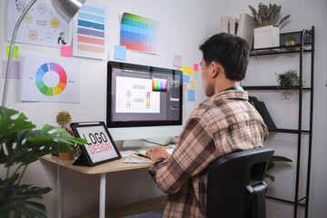 Graphic Designer Focused on Creating Logo Using Computer and Design Tablet in Modern Home Office