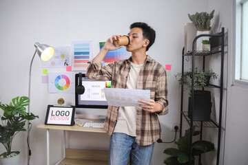 Young Man Concentrating on Digital Design With Tablet, Surrounded by Color Charts and Creative Tools