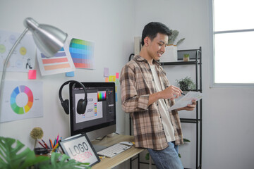 Designer Uses Stylus and Tablet to Work on Logo Concept With Computer Monitor Visible