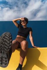 Young sporty woman relaxing after workout outdoors, touching her forehead and smiling