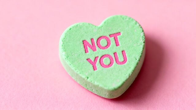 Light green heart-shaped candy with 'not you' message on a pink background